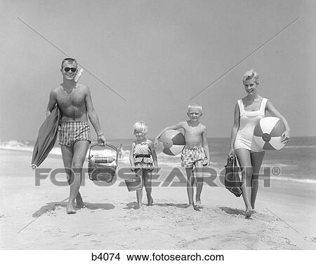 1950S Family Of Four Walking Towards Camera With Beach Balls Umbrella Picnic Basket And Sand Bucket View Large Photo Image Picture - 1950S Family Of Four Walking Towards Camera With Beach Balls Umbrella Picnic Basket And Sand Bucket. Fotosearch