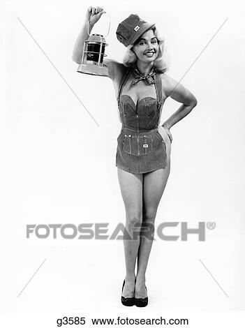 Stock Photography - 1950S Full Length Portrait Of Blond Woman Dressed In Railroad Apron & Cap Holding Signal Lamp Pinup. Fotosearch