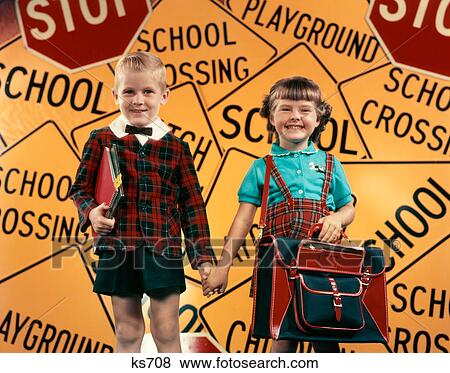 1950S Girl And Boy With Book Bag And Books Holding Hands Together In Front Of School And Traffic Warning Signs In Studio View Large Photo Image Stock Photo - 1950S Girl And Boy With Book Bag And Books Holding Hands Together In Front Of School And Traffic Warning Signs In Studio . Fotosearch