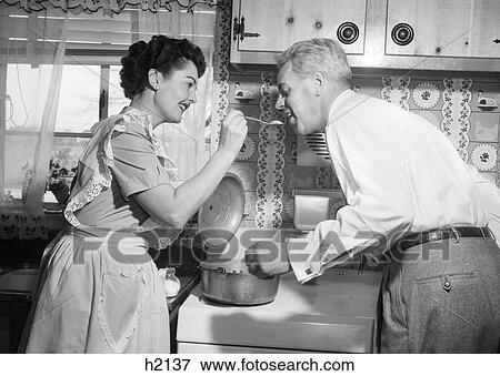 1950S Housewife In Kitchen Having Husband Taste Food On Stove View Large Photo Image Stock Photo - 1950S Housewife In Kitchen Having Husband Taste Food On Stove. Fotosearch