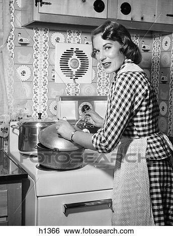1950S Housewife Wearing Checkered Dress Standing In Kitchen Stirring Pot On Stove Looking Over Shoulder View Large Photo Image Stock Photograph - 1950S Housewife Wearing Checkered Dress Standing In Kitchen Stirring Pot On Stove Looking Over Shoulder. Fotosearch