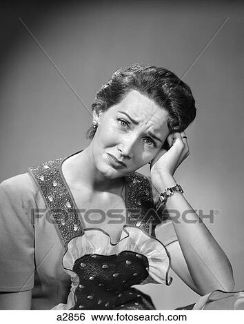 Stock Photograph - 1950S Housewife Woman In Print Apron Hand Up To Temple Headache Pain Sad Depressed Facial Expression Worried Serious. Fotosearch