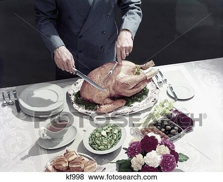 1950S Male Hands About To Carve Thanksgiving Turkey Table Setting Plates Gravy Rolls Olives Crudites View Large Photo Image Stock Photo - 1950S Male Hands About To Carve Thanksgiving Turkey Table Setting Plates Gravy Rolls Olives Crudites . Fotosearch