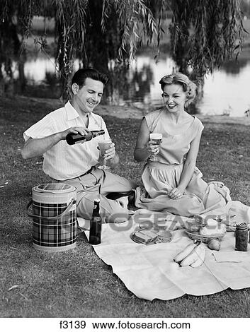 Stock Photo - 1950S Man Woman Couple Having A Summer Picnic Outdoors Drinking Beer. Fotosearch