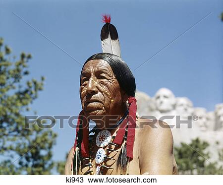 Stock Image - 1950S Native American Sioux Indian In The Black Hills Mount Rushmore In Background South Dakota Usa. Fotosearch