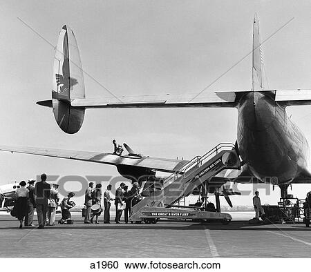 Stock Image - 1950S People Boarding Constellation Style Airplane Double Tail Outdoor . Fotosearch