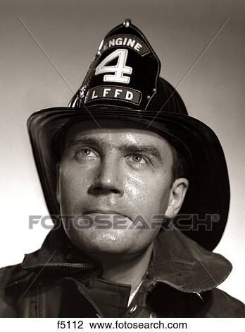 Stock Image - 1950S Portrait Fireman Serious Expression Metal Fire Hard Hat Engine 4. Fotosearch