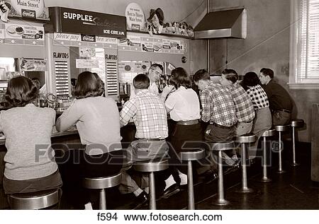 1950S Rear View Of Group Of Teenage Boys & Girls Sitting Together At A Soda Fountain Malt Shop Counter Snack Food View Large Photo Image Picture - 1950S Rear View Of Group Of Teenage Boys & Girls Sitting Together At A Soda Fountain Malt Shop Counter Snack Food. Fotosearch