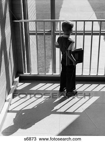 1950S Schoolboy With Books Under Arm Looking Out Window Between Bars Of Railing Shadow Cast Behind Him View Large Photo Image Stock Image - 1950S Schoolboy With Books Under Arm Looking Out Window Between Bars Of Railing Shadow Cast Behind Him. Fotosearch