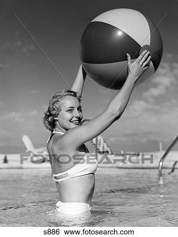 1950S Side View Of Blonde In White Bikini Standing In Pool In Waist-High Water Holding Beach Ball In Air View Large Photo Image Stock Photograph - 1950S Side View Of Blonde In White Bikini Standing In Pool In Waist-High Water Holding Beach Ball In Air. Fotosearch