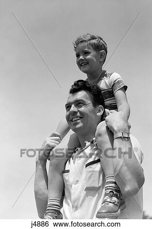 Stock Photograph - 1950S Smiling Father Carrying Son On Shoulders Outdoor. Fotosearch