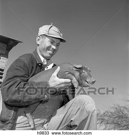 1950S Smiling Man Farmer Wearing Hat Work Jacket Denim Striped Overalls Holding Duroc Piglet On His Knees View Large Photo Image Stock Image - 1950S Smiling Man Farmer Wearing Hat Work Jacket Denim Striped Overalls Holding Duroc Piglet On His Knees. Fotosearch