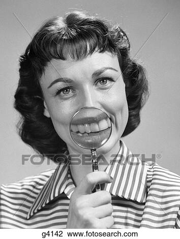 Stock Image - 1950S Smiling Portrait Brunette Woman Holding Magnifying Glass To Mouth. Fotosearch