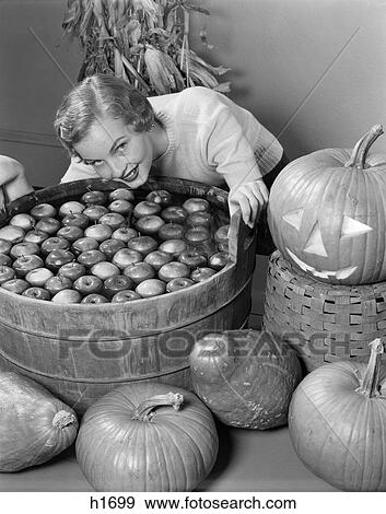 1950S Smiling Woman Leaning Over Wooden Tub Filled With Water About To Begin Bobbing For Apples View Large Photo Image Stock Photo - 1950S Smiling Woman Leaning Over Wooden Tub Filled With Water About To Begin Bobbing For Apples. Fotosearch