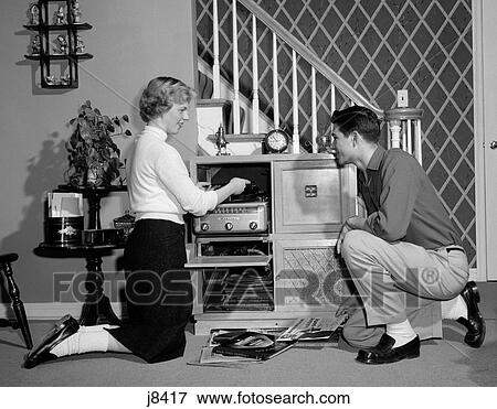 Stock Photo - 1950S Teenage Couple Playing Hi-Fi Records On Console Phonograph In Living Room. Fotosearch