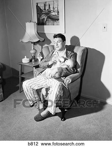 Stock Image - 1950S Tired Father Giving Baby Bottle At Nighttime Feeding. Fotosearch