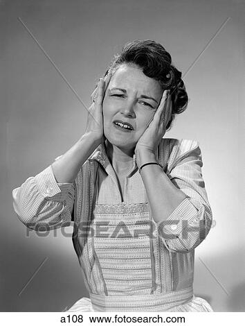Stock Photo - 1950S Woman In Cotton Dress With Both Hands Over Her Ears Holding Her Frowning Head. Fotosearch