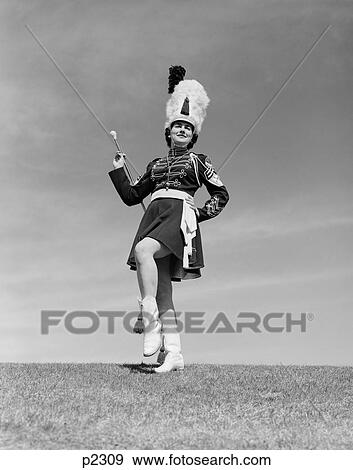 1950S Woman Majorette In Uniform With Short Skirt Boots Tall Furry Hat Posing Outdoors Holding A Baton View Large Photo Image Stock Photo - 1950S Woman Majorette In Uniform With Short Skirt Boots Tall Furry Hat Posing Outdoors Holding A Baton. Fotosearch