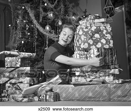 1950S Woman Sitting By Christmas Tree Hugging Pile Of Presents View Large Photo Image Stock Photo - 1950S Woman Sitting By Christmas Tree Hugging Pile Of Presents. Fotosearch
