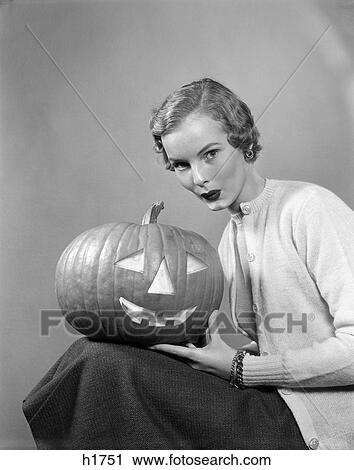 1950S Woman Wearing Sweater Holding Carved Pumpkin Jack-O-Lantern On Her Lap View Large Photo Image Stock Image - 1950S Woman Wearing Sweater Holding Carved Pumpkin Jack-O-Lantern On Her Lap. Fotosearch
