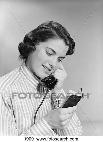 1950S Young Woman Talking On Telephone Reading Address From Little Black Book View Large Photo Image Stock Photo - 1950S Young Woman Talking On Telephone Reading Address From Little Black Book. Fotosearch