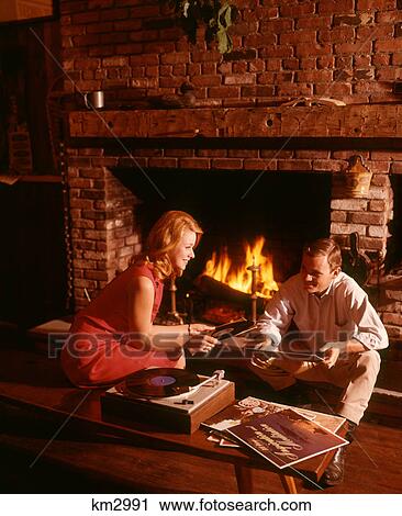 1960S 1970S Couple Man Woman By Living Room Fireplace Playing Vinyl Record Album Music On High Fidelity Stereo Turntable View Large Photo Image Stock Image - 1960S 1970S Couple Man Woman By Living Room Fireplace Playing Vinyl Record Album Music On High Fidelity Stereo Turntable. Fotosearch