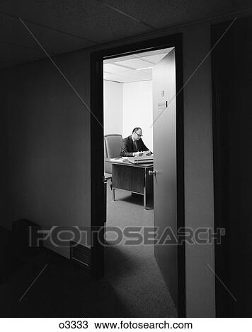 1960S 1970S Executive Businessman At Desk Seen Working Late Through Door Ajar View Large Photo Image Stock Image - 1960S 1970S Executive Businessman At Desk Seen Working Late Through Door Ajar . Fotosearch