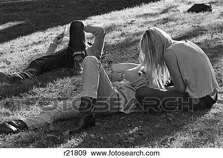 Stock Photo - 1960S 1970S Hippie Couple Woman With Long Blonde Hair Sit Beside Man Lying In Grass. Fotosearch