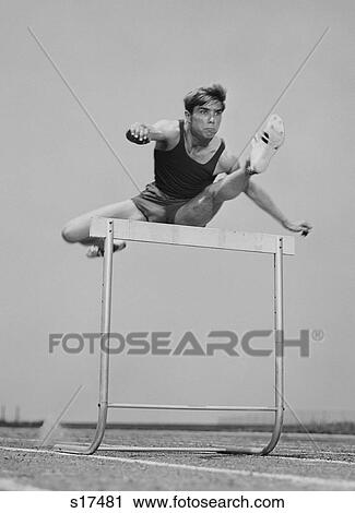 Stock Image - 1960S 1970S Running Man Jumping Over Hurdle. Fotosearch