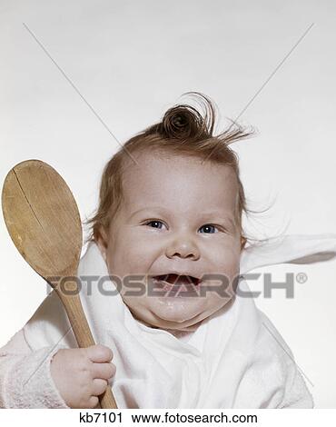 1960S 1970S Smiling Baby Wearing Bib And Holding Wooden Spoon View Large Photo Image Stock Image - 1960S 1970S Smiling Baby Wearing Bib And Holding Wooden Spoon. Fotosearch