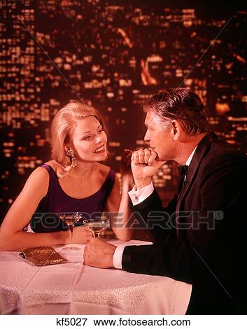 1960S 1970S Smiling Romantic Couple Mature Man Blond Woman In Formal Evening Dress In A Nightclub Drinking Champagne View Large Photo Image Stock Photo - 1960S 1970S Smiling Romantic Couple Mature Man Blond Woman In Formal Evening Dress In A Nightclub Drinking Champagne. Fotosearch