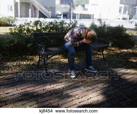 1960S 1970S Troubled Teenage Boy With Long Hair And Headband Sitting On City Park Bench Holding Face In Hands View Large Photo Image Picture - 1960S 1970S Troubled Teenage Boy With Long Hair And Headband Sitting On City Park Bench Holding Face In Hands. Fotosearch