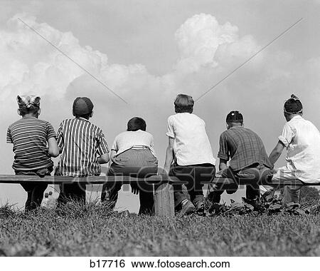 Stock Photograph - 1960S Back View Of Six Boy Baseball Players Sitting On Bench. Fotosearch