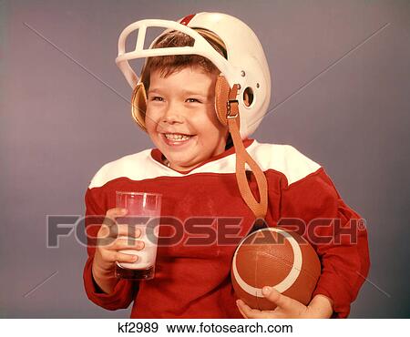 1960S Boy Drinking Milk Wearing Football Helmet Red Jersey Holding Ball View Large Photo Image Stock Photo - 1960S Boy Drinking Milk Wearing Football Helmet Red Jersey Holding Ball. Fotosearch