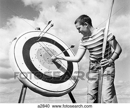 1960S Boy Jeans Striped T-Shirt Holding Bow & Pulling Arrow Out Of Target Bull'S-Eye View Large Photo Image Stock Image - 1960S Boy Jeans Striped T-Shirt Holding Bow & Pulling Arrow Out Of Target Bull'S-Eye . Fotosearch