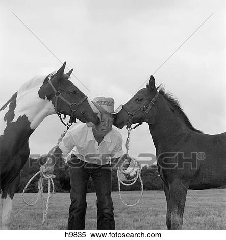 1960S Boy Wearing Cowboy Hat Holding Ropes Reins Harness Halter Of 2 Horses One On Either Side Of His Face Kissing Him Funny View Large Photo Image Stock Photography - 1960S Boy Wearing Cowboy Hat Holding Ropes Reins Harness Halter Of 2 Horses One On Either Side Of His Face Kissing Him Funny. Fotosearch