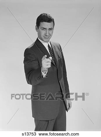 Stock Image - 1960S Business Man Pointing Finger Toward Camera Serious Facial Expression Looking At Camera. Fotosearch