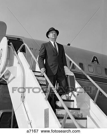 1960S Businessman Deplaning From Airplane Wearing Hat And Carrying Overcoat And Briefcase View Large Photo Image Stock Photo - 1960S Businessman Deplaning From Airplane Wearing Hat And Carrying Overcoat And Briefcase. Fotosearch