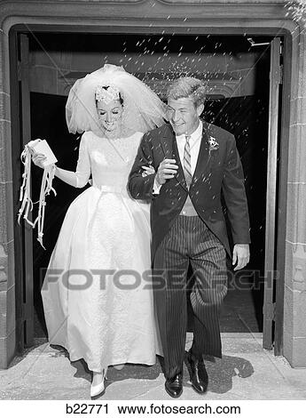 1960S Couple Bride And Groom Arm In Arm Leaving Church Under Shower Of Rice View Large Photo Image Stock Image - 1960S Couple Bride And Groom Arm In Arm Leaving Church Under Shower Of Rice. Fotosearch