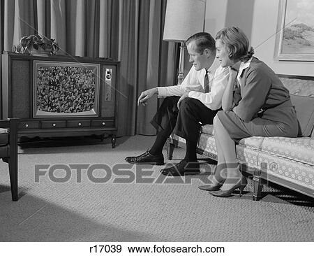 1960S Couple Man Woman Sitting On Couch Watching Television View Large Photo Image Stock Photo - 1960S Couple Man Woman Sitting On Couch Watching Television. Fotosearch