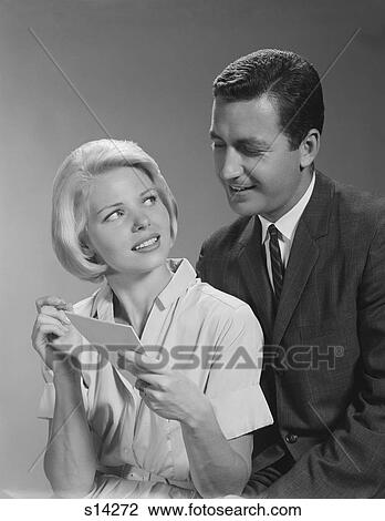 Stock Image - 1960S Couple Reading List Man Looking Over Woman’S Shoulder. Fotosearch