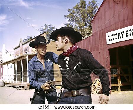 1960S Cowboy Sheriff With Badge Draws Gun Arrests Gunfighter In Front Of Livery Stable View Large Photo Image Stock Image - 1960S Cowboy Sheriff With Badge Draws Gun Arrests Gunfighter In Front Of Livery Stable. Fotosearch