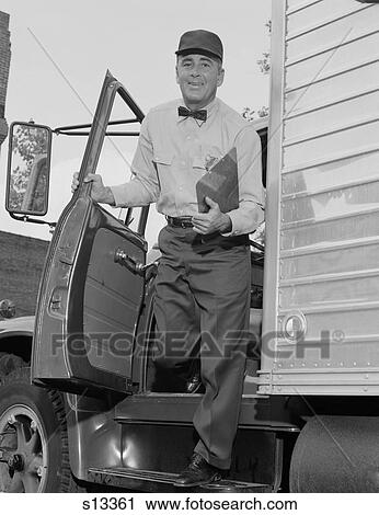 Stock Image - 1960S Delivery Man Stepping Out Of Truck Holding Clipboard Looking At Camera. Fotosearch
