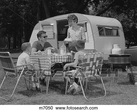 Stock Image - 1960S Family Camping Eating Meal Beside Rv Camper. Fotosearch