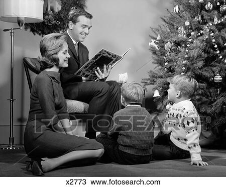 1960S Family Father Mother Two Sons Smiling Sitting By Christmas Tree In Living Room Reading A Book View Large Photo Image Stock Image - 1960S Family Father Mother Two Sons Smiling Sitting By Christmas Tree In Living Room Reading A Book. Fotosearch