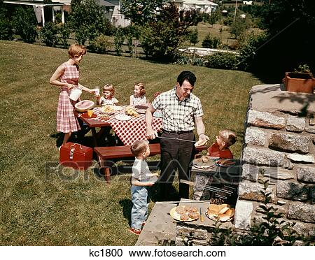 Stock Image - 1960S Family Father Mother Two Daughters Two Sons Backyard Bar-B-Que Outdoor. Fotosearch
