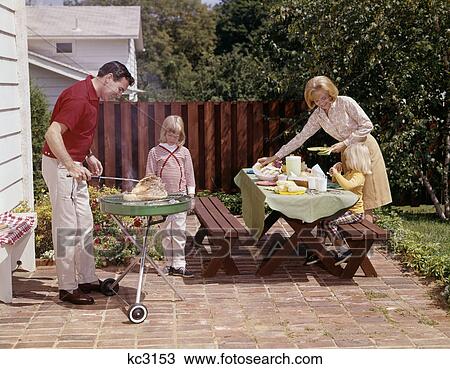 1960S Family Father Mother Two Daughters Barbeque In Backyard On Brick Patio View Large Photo Image Stock Image - 1960S Family Father Mother Two Daughters Barbeque In Backyard On Brick Patio . Fotosearch