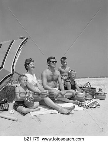 1960S Family Portrait Mother Father Daughter And Two Sons Sitting On Beach Under Umbrella View Large Photo Image Stock Photo - 1960S Family Portrait Mother Father Daughter And Two Sons Sitting On Beach Under Umbrella. Fotosearch