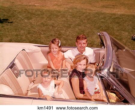 Stock Image - 1960S Family Sitting Smiling In Open White Convertible Automobile . Fotosearch