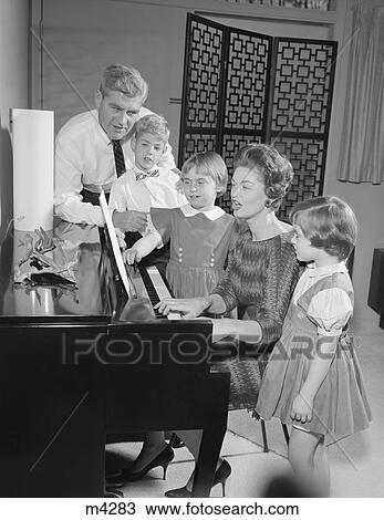 Stock Image - 1960S Family Standing Around Piano Singing. Fotosearch
